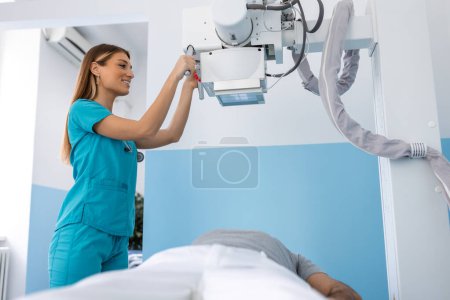 Foto de Doctor mirando la máquina de rayos X en la clínica. La doctora pone la máquina en rayos X sobre el paciente. Radiólogo y paciente en sala de rayos X. - Imagen libre de derechos