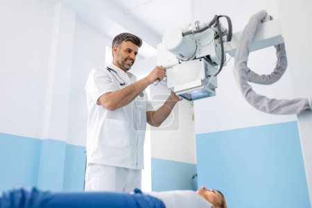 Téléchargez les photos : Radiologistes multiethniques avec une jeune patiente aux rayons X, Radiologiste installant la machine sur une patiente aux rayons X - en image libre de droit