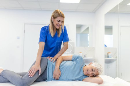 Photo for Professional chiropractor or physiotherapist helps to heal a senior woman's back. Doctor fixes the patient lying on a couch of a modern rehabilitation clinic Concept of physical rehabilitation. - Royalty Free Image