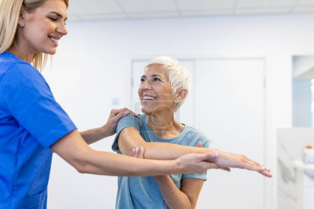 Photo for Photo of physiotherapist working with a senior female patient in her office during the day. Physiotherapist helping female patient during muscle rehabilitation physiotherapy - Royalty Free Image