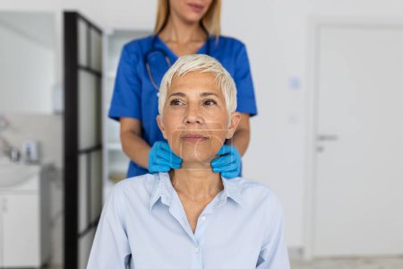 Photo for Friendly woman doctor wearing gloves checking sore throat or thyroid glands, touching neck of senior female patient visiting clinic office. Thyroid cancer prevention concept - Royalty Free Image