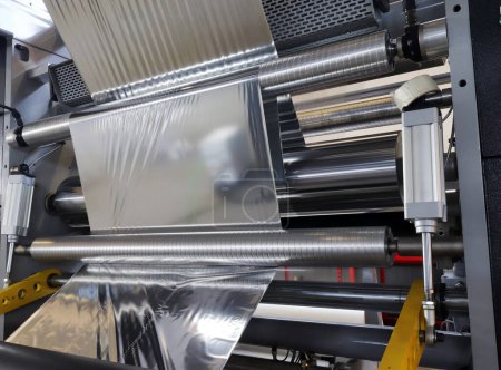 Téléchargez les photos : Rouleau de papier d'aluminium pour l'emballage alimentaire sur la machine d'emballage automatique dans l'usine de produits alimentaires. - en image libre de droit