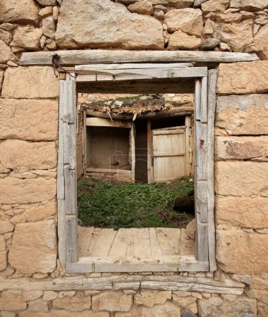 Foto de Arruinada casa de piedra. Puerta y armario de madera visibles desde la ventana. - Imagen libre de derechos