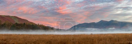 Photo for Epic Autumn sunrise landscape image looking from Manesty Park in Lake Distict towards sunlit Skiddaw Range with mit rolling across Derwentwater surface - Royalty Free Image