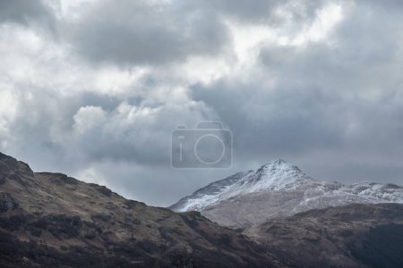 Téléchargez les photos : Belle image de paysage du sommet enneigé de la montagne Ben Lomond dans les Highlands écossais avec un ciel dramatique au-dessus - en image libre de droit