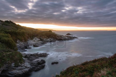 Téléchargez les photos : Moody paysage lever de soleil image à Prussia Cove en Cornouailles Angleterre avec ciel atmosphérique et océan - en image libre de droit