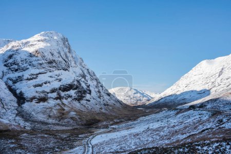 Téléchargez les photos : Beau paysage d'hiver ciel bleu image de vue le long de Glencoe Rannoch Moor vallée avec des montagnes couvertes de neige tout autour - en image libre de droit