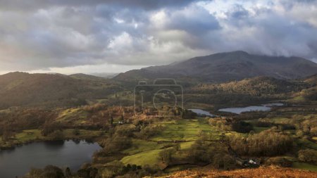 Photo for Beautiful Winter sunrise landscape view from Loughrigg Fell across Loughrigg Tarn with colorful dappled sunlight - Royalty Free Image
