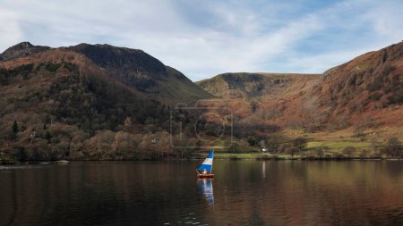 Téléchargez les photos : Beautiful Winter landscape views of mountain ranges around Ullswater in Lake District viewed from boat on lake with unidentified person on solo sialing boat - en image libre de droit