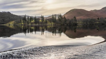Téléchargez les photos : Beautiful Winter landscape image viewed from boat on Ullswater in Lake District with unusual water ripple wake movements - en image libre de droit