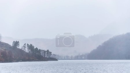 Photo for Beautiful calm peaceful Winter landscape over Thirlmere in Lake District with fog and layers of trees visible in the distance - Royalty Free Image