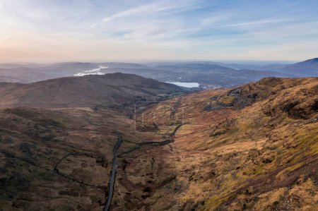 Foto de Aerial drone landscape image of sunrise Winter view from Red Screes in Lake District looking towards Windermere in the distance over Wansfell Pike peak - Imagen libre de derechos