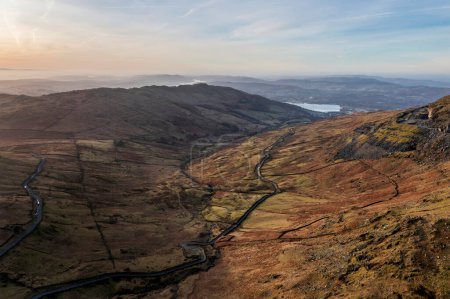 Photo for Aerial drone landscape image of sunrise Winter view from Red Screes in Lake District looking towards Windermere in the distance over Wansfell Pike peak - Royalty Free Image