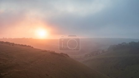Téléchargez les photos : Incroyable lever de soleil d'été de la digue du diable dans le parc national de South Downs dans la campagne anglaise avec des nuages bas donnant un sentiment d'humeur - en image libre de droit