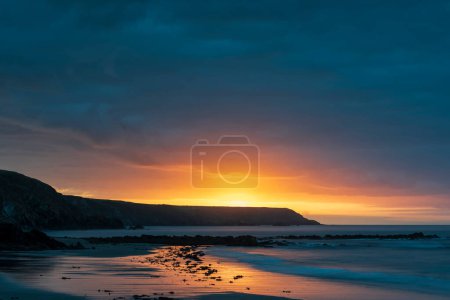 Photo for Absolutely stunning sunrise landscape image of Kennack Sands in Cornwall UK wuth dramatic moody clouds and vibrant sunburst - Royalty Free Image