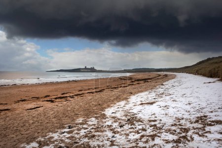 Beautiful unusual moody Winter landscape of snow on Embleton Bay beach in Northumberland England