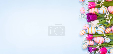 Photo for Easter holiday background with colorful easter eggs and tulip flowers on blue background. Top view from above. Easter eggs with colorful tulip flower on blue backround. - Royalty Free Image