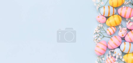 Photo for Easter holiday background with colorful easter eggs and white flowers on blue background. Top view from above. Easter eggs with white flower on blue backround. - Royalty Free Image