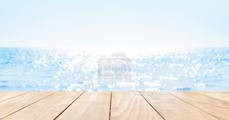 Photo for Wooden table top on blue summer sparking sea water with bokeh light. Blur shiny sea water and summer sky background. - Royalty Free Image