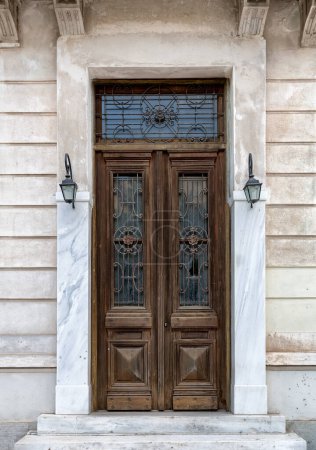 Photo for Vintage brown wooden old door in the centre of Athens in Greece. Wooden textured big door with two lights. - Royalty Free Image