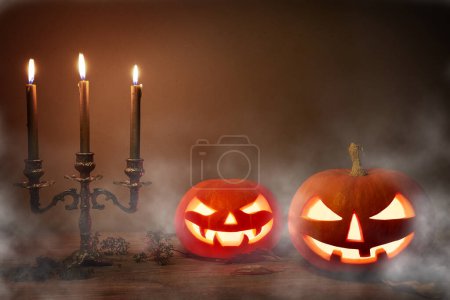 Photo for Halloween pumpkin head jack-o-lantern on wooden background. Spooky halloween pumpkins, Jack O Lantern, with an evil face and eyes and old candles with a mist on dark background. - Royalty Free Image