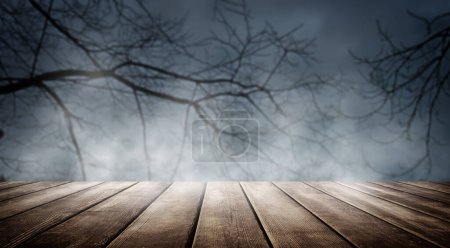 Photo for Spooky misty horror Halloween background with empty wooden planks, for product placement. Old wooden table and dead tree silhouette at night for Halloween background. - Royalty Free Image