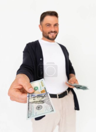 Foto de Joven hombre exitoso extendiendo su mano con un billete de 100 dólares sobre un fondo blanco. Un hombre presta 100 dólares. - Imagen libre de derechos
