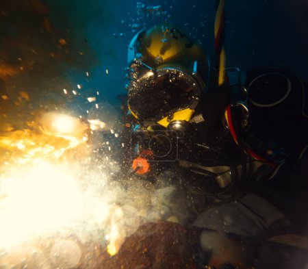 Commercial diver welding underwater at construction site