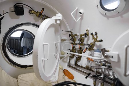 Interior of a white hyperbaric chamber with airlock angle shot