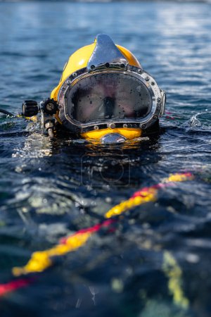 Commercial diver in helmet gazes at camera closeup