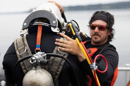 Diver assisted by tender before water entry closeup