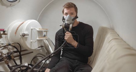 Military man receiving treatment in industrial hyperbaric chamber closeup