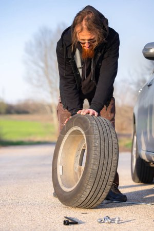 Man holding spare tire at roadside pitstop closeup