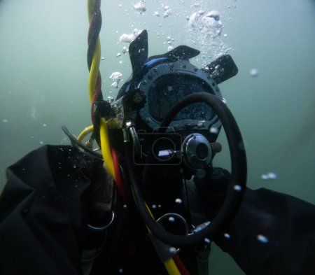 Buzo comercial en casco trabajando en primer plano bajo el agua