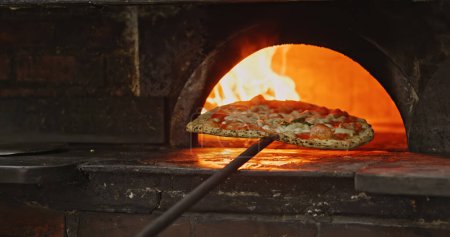 Removing authentic neapolitan pizza from wood-fired oven closeup