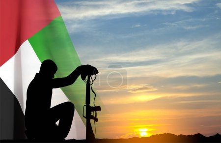 Foto de Silueta de un soldado arrodillado con bandera de los EAU contra el atardecer. Concepto - EAU fiestas nacionales, Día Nacional, Día de la Conmemoración - Imagen libre de derechos