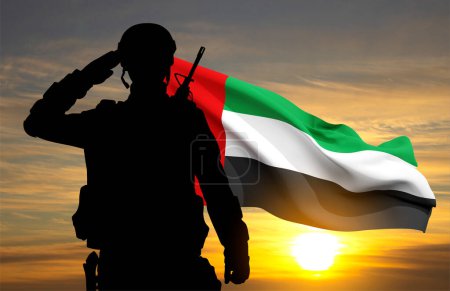 Foto de Silueta de un soldado saludando con la bandera de los Emiratos Árabes Unidos contra la puesta del sol. Fuerzas armadas de los Emiratos Árabes Unidos. Concepto para el Día de la Conmemoración, Día de los Mártires, Día Nacional - Imagen libre de derechos