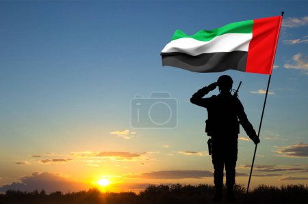 Foto de Silueta de saludo soldado con la bandera de los Emiratos Árabes Unidos contra la puesta del sol. Fuerzas armadas de los Emiratos Árabes Unidos. Concepto para el Día de la Conmemoración, Día de los Mártires, Día Nacional - Imagen libre de derechos