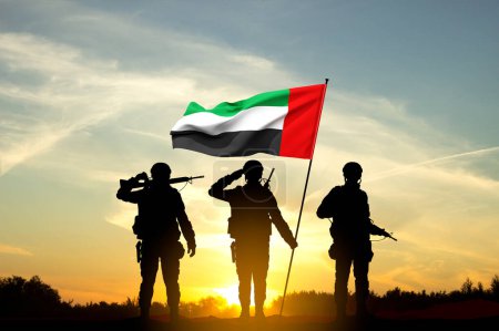 Foto de Siluetas de soldados con la bandera de los Emiratos Árabes Unidos contra la puesta del sol. Fuerzas armadas de los Emiratos Árabes Unidos. Concepto para el Día de la Conmemoración, Día de los Mártires, Día Nacional - Imagen libre de derechos
