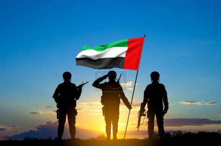 Foto de Siluetas de soldados con la bandera de los Emiratos Árabes Unidos contra la puesta del sol. Fuerzas armadas de los Emiratos Árabes Unidos. Concepto para el Día de la Conmemoración, Día de los Mártires, Día Nacional - Imagen libre de derechos