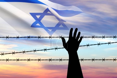 Holocaust Remembrance Day. Silhouette of hand with barber wire on a sunset with Israel flag