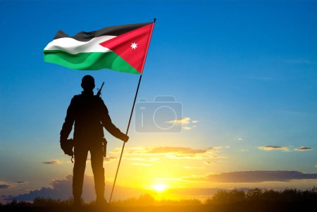 Téléchargez les photos : Silhouette d'un soldat tenant un drapeau jordanien contre le coucher du soleil - en image libre de droit
