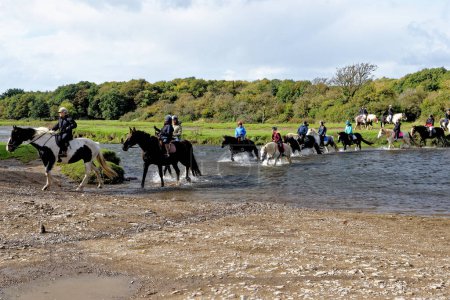 Téléchargez les photos : Cavaliers traversant la rivière Ewenny Ogmore Castle. Ogmore by Sea, Glamorgan, Pays de Galles, Royaume-Uni - 15 octobre 2022 - en image libre de droit