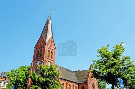 Foto de Iglesia Evangélica Luterana - La torre neogótica de la iglesia Warnemunde se eleva por encima de la ciudad costera báltica de Rostock, Alemania - Imagen libre de derechos