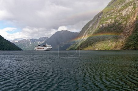 Téléchargez les photos : Rainbow over MSC Lirica Cruise ship in Norwegian Fjords - Geiranger fjord - Hellesylt, Sunnylvsfjord, Norway, Scandinavia. Travel destination Norway. 02.07.2012 - en image libre de droit