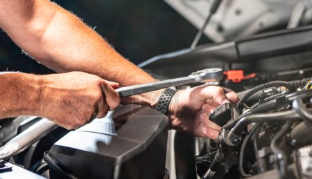 Foto de Auto mechanic working on car engine in mechanics garage. Repair service. authentic close-up shot - selective focus with motion blur - Imagen libre de derechos