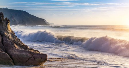Téléchargez les photos : Close up shot of waves hitting the coastline of portugal at the beach at calm orange sunset ocean. surreal selective focus shot - en image libre de droit