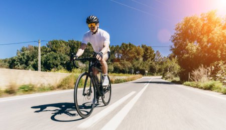 Téléchargez les photos : Homme Adulte sur un vélo de course escalade la colline à la mer Méditerranée paysage route côtière sur Mallorca Baléares île - en image libre de droit
