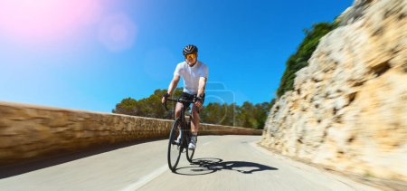 Téléchargez les photos : Homme Adulte sur un vélo de course escalade la colline à la mer Méditerranée paysage route côtière sur Mallorca Baléares île - en image libre de droit