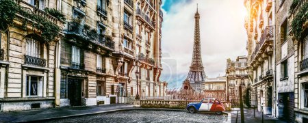 Foto de Pequeña calle paris con vista a la famosa torre paris eifel en un día nublado lluvioso con un poco de sol - citroen 2CV en colores tricolores nacionales franceses. - Imagen libre de derechos